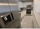 Close-up of a modern kitchen with stainless steel appliances, white cabinets, and tile flooring at 6517 Summer Cove Dr, Riverview, FL 33578