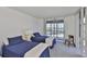 Bright bedroom featuring twin beds, carpet flooring, and sliding glass doors to a balcony with water views at 7400 Sun Island S Dr # 412, South Pasadena, FL 33707
