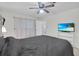Bedroom with ceiling fan, window, grey comforter and television with a tropical scene at 7708 Fairlawn Dr, Hudson, FL 34667
