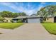 Charming single-story home with well-maintained lawn, mature trees, and an attached two car garage at 7708 Fairlawn Dr, Hudson, FL 34667