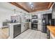 Bright kitchen with stainless steel appliances, light gray cabinetry, wood accent ceiling, and an eat-in island at 9115 Panda Ln, Port Richey, FL 34668