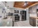 Modern kitchen featuring stainless steel appliances, gray cabinets, wood ceiling accent and white tile flooring at 9115 Panda Ln, Port Richey, FL 34668