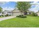 Beautifully landscaped front yard with green grass, plants, and a charming home at 10232 Buncombe Way, San Antonio, FL 33576