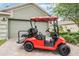 Garage exterior featuring a red golf cart, brick driveway, and well-maintained landscaping at 10232 Buncombe Way, San Antonio, FL 33576