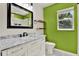 Updated bathroom with modern vanity, designer mirror, floating shelves, and bright green accent wall at 10314 Deepbrook Dr, Riverview, FL 33569