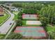 Aerial view of a community with tennis, basketball, and volleyball courts, surrounded by lush greenery at 10422 Fenceline Rd, New Port Richey, FL 34655