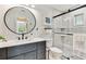Modern bathroom featuring gray vanity, round mirror, and glass-enclosed walk-in shower at 1286 Stony Brook Ln, Dunedin, FL 34698