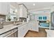 Bright white kitchen featuring stainless steel appliances, gray backsplash, and wood-look floors at 1286 Stony Brook Ln, Dunedin, FL 34698