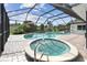A covered pool and hot tub surrounded by brick pavers with an outdoor screened enclosure at 1286 Stony Brook Ln, Dunedin, FL 34698