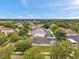 An aerial view showing a pool with screen enclosure, lush landscaping, mature trees and other houses in the distance at 1328 Rushgrove Cir, Dover, FL 33527