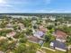 An aerial view showcases a community with mature trees, homes with screened pools, and a serene lake backdrop on a clear day at 1328 Rushgrove Cir, Dover, FL 33527