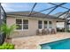Lush backyard with screened pool area featuring paved deck, seating, and partial view of the home's exterior at 1328 Rushgrove Cir, Dover, FL 33527