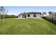 Lush backyard with a modern home featuring a pool, green lawn, and privacy fencing at 14009 Wenzel Ave, Port Charlotte, FL 33981
