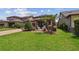 Well-maintained backyard featuring a covered patio, lush lawn, palm trees, and decorative landscaping at 14110 Barrington Stowers Dr, Lithia, FL 33547
