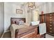 Bright bedroom with wooden bed frame, light walls, and decorative wooden lighting fixture at 14110 Barrington Stowers Dr, Lithia, FL 33547