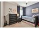 Cozy bedroom with carpeted floor, dark blue accent wall, dresser and a twin bed with storage underneath at 14110 Barrington Stowers Dr, Lithia, FL 33547