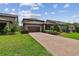 Beautifully landscaped home with a brick driveway, lush green lawn, and inviting curb appeal at 14110 Barrington Stowers Dr, Lithia, FL 33547