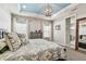 Comfortable main bedroom featuring tray ceiling, stylish chandelier, and ensuite bathroom entrance at 14110 Barrington Stowers Dr, Lithia, FL 33547