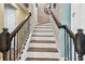 Staircase with white risers, wooden treads and decorative metal balusters leading upstairs at 14110 Barrington Stowers Dr, Lithia, FL 33547