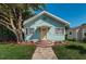 Charming bungalow featuring a manicured lawn, mature tree, and inviting yellow door at 1525 38Th N Ave, St Petersburg, FL 33704
