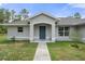 Inviting front entrance with a covered porch, a blue door and manicured landscaping at 16473 Scaup Duck Ave, Weeki Wachee, FL 34614