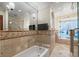 Elegant bathroom boasts a tub, glass shower, neutral tile, and intricate mosaic accents for a luxurious feel at 1721 Allens Creek Dr, Clearwater, FL 33764