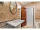 Stylish bathroom featuring a pedestal sink, decorative mirror, and textured walls at 1721 Allens Creek Dr, Clearwater, FL 33764