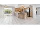 Bright eat-in kitchen with white tile flooring, wood cabinets, and stainless steel refrigerator at 1839 Neptune Dr, Englewood, FL 34223