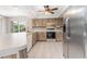 Well-lit kitchen with stainless refrigerator, white appliances, and wooden cabinets at 1839 Neptune Dr, Englewood, FL 34223