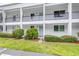 Inviting condo exterior with white facade, black railings, and lush landscaping at 2060 Marilyn St # 114, Clearwater, FL 33765