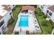 Aerial view of community pool with tables, umbrellas, and lounge chairs surrounded by lush green landscaping at 2060 Marilyn St # 114, Clearwater, FL 33765