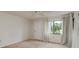 Bright bedroom featuring neutral walls, carpet, ceiling fan, and a window providing natural light and pleasant outdoor views at 210 Martha Ln # 210, Oldsmar, FL 34677
