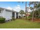 Rear exterior of condo building with lush green lawn, mature trees, screened patios, and multiple AC units at 210 Martha Ln # 210, Oldsmar, FL 34677
