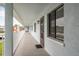 Exterior hallway view featuring a brown door, window with blinds, and a white railing and support beams at 210 Martha Ln # 210, Oldsmar, FL 34677