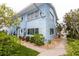 Corner view of a light blue building showing the side entrance with stairway surrounded by lush landscaping at 241 Skiff Pt # 1, Clearwater Beach, FL 33767