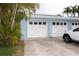 Attached garage with white door and a parking area, surrounded by tropical foliage at 241 Skiff Pt # 1, Clearwater Beach, FL 33767