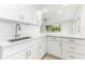Modern kitchen featuring white cabinets, quartz countertops, stainless steel sink, and tile backsplash, offering a clean design at 241 Skiff Pt # 1, Clearwater Beach, FL 33767