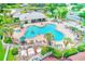 Aerial view of a community pool with lush landscaping, lounge seating, and a spacious clubhouse at 25729 Aldus Dr, Land O Lakes, FL 34639