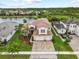 Aerial view of a two-story home showcasing a paver driveway, manicured landscaping, and nearby lake at 2724 Coco Palm Cir, Wesley Chapel, FL 33543