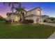 Stunning two-story home with a three-car garage, lush landscaping, and mature palm trees at sunset at 2724 Coco Palm Cir, Wesley Chapel, FL 33543
