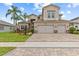 Elegant two-story home with a three-car garage, paved driveway, mature landscaping, and a tile roof at 2724 Coco Palm Cir, Wesley Chapel, FL 33543