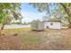 Backyard with green grass, mature trees, a shed, and the white exterior of the house at 4220 E Regnas Ave, Tampa, FL 33617