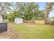 Backyard with green grass, a wooden fence, trees, and a shed at 4220 E Regnas Ave, Tampa, FL 33617