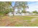 Front yard with mature trees, green grass, and the front view of the house at 4220 E Regnas Ave, Tampa, FL 33617