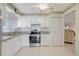 Updated kitchen with white cabinets, stainless steel appliances, granite counters, and tile floors leading into the living space at 4512 Superior Ln, Clearwater, FL 33762
