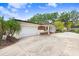 Home featuring a long driveway leading up to an attached garage, complemented by a charming front porch at 4640 W Lamb Ave, Tampa, FL 33629