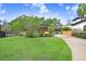 Charming single-Gathering home boasts a lush green lawn, mature trees, and an extended driveway leading to the house at 4640 W Lamb Ave, Tampa, FL 33629