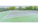 Outdoor tennis court with green and gray surface surrounded by tall trees and mesh fencing at 5501 80Th N St # 206, St Petersburg, FL 33709