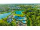 An aerial view shows a community pool area with many amenities and a playground near a pond at 5624 Fisher Glen Loop, Wesley Chapel, FL 33545