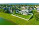 Aerial view of a fenced backyard with green lawn, a fire pit and mature trees near a pond at 5624 Fisher Glen Loop, Wesley Chapel, FL 33545